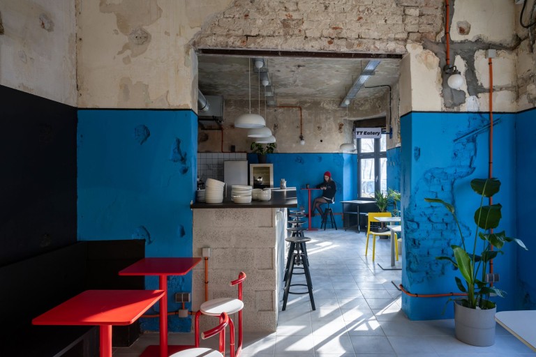 TT-Eatery cafe dining area with colorful walls, red tables and an open ceiling