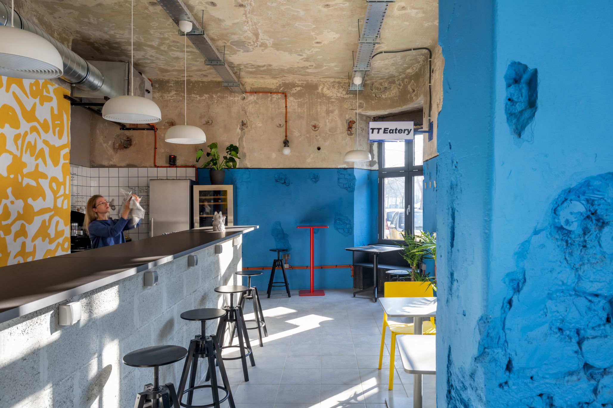 TT-Eatery cafe interior with yellow and blue walls, red furniture and exposed ceiling